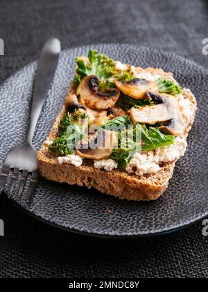 Ricotta végétalien maison, champignons et Kale sur le pain grillé Banque D'Images