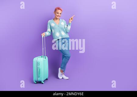 Plein corps photo cadre de jeune femme positive sourire indiquer doigt recommander agence de voyage maquette isolée sur fond violet couleur Banque D'Images