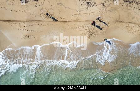 Paysage aérien de drone de personnes non reconnues marchant dans une plage de sable en hiver. Des vagues venteuses s'écrasant sur le rivage Banque D'Images