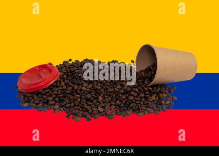 Une tasse en papier jetable retournée avec un couvercle rempli de grains de café torréfiés sur le fond du drapeau colombien (gros plan) Banque D'Images