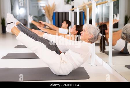 Groupe de personnes pratiquant l'équilibrage des postures de yoga sur des tapis en studio de danse Banque D'Images