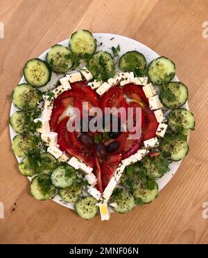 Assiette de concombres, tomates, fromage feta et olives en forme de coeur, sur une table en bois, Allemagne Banque D'Images