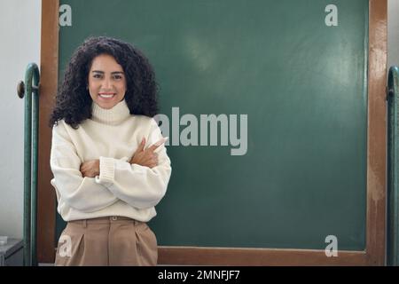 Jeune femme d'affaires heureuse enseignante pointant sur un tableau noir vide. Banque D'Images