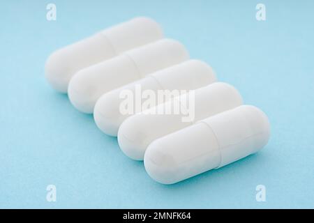 Capsule de gel. Capsule de médecine blanche sur fond bleu clair. supplément alimentaire, concept de pharmacie. Banque D'Images