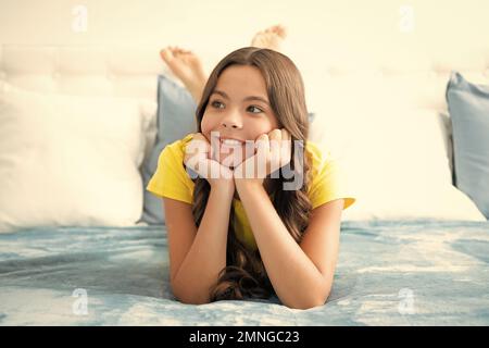 Enfant rêvant, rêvant. Adolescent fille de repos dans le lit à la chambre à la maison. Enfant se détendant à l'intérieur de la chambre. Banque D'Images