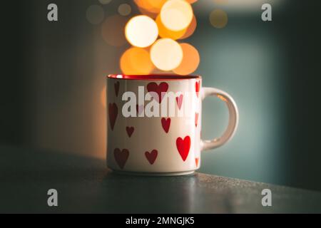 Une tasse de thé ou de café avec des coeurs est debout sur une table avec du bokeh en arrière-plan. Saint Valentin ou concept d'amour. Banque D'Images