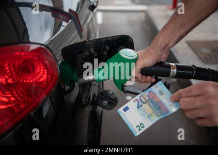 Main d'un homme ravitaillant la voiture et tenant un billet de 20€, concept de la hausse des prix du carburant Banque D'Images