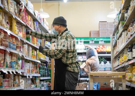 Un travailleur à la Takoma Park Silver Spring Co-op dans le Maryland fronting stock sur les étagères de l'épicerie ca. Novembre 2022 Banque D'Images