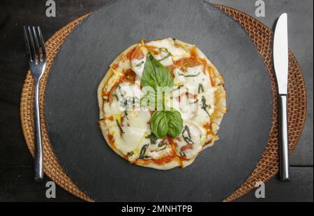 Pizza Margherita avec tomates, basilic et fromage mozzarella sur plateau en pierre noire Banque D'Images