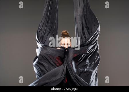 Jeune acrobat qui se produit avec des silks aériens Banque D'Images