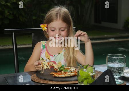 Petite fille mangeant de la pizza Margherita au restaurant Banque D'Images