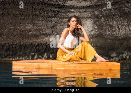 Belle femme assise sur un radeau en bois sur l'étang Banque D'Images