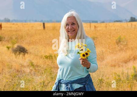 États-Unis, Idaho, Bellevue, Portrait d'une femme âgée tenant un bouquet de tournesols Banque D'Images