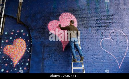 Australian street artist James Cochran also known as Jimmy C, works on his mural of eight hearts on a Network Rail wall at Borough Market in London, Sunday, March 25, 2018. (AP Photo/Kirsty Wigglesworth)
