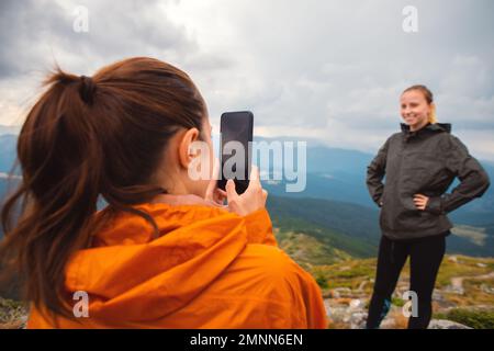 Deux amis jeune femme amis randonneurs contre les montagnes prendre une photo un iphone dans la nature, Selfie smartphone moderne, en utilisant le téléphone, amitié Banque D'Images