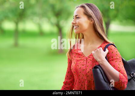 Être à l'extérieur la rend heureuse. une jeune femme se promenant dans le parc. Banque D'Images