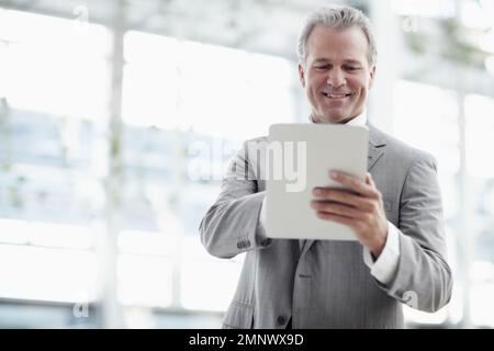 Qui dit que vous ne pouvez pas enseigner de nouvelles astuces à un vieux chien. Homme d'affaires mature utilisant une tablette numérique au bureau. Banque D'Images