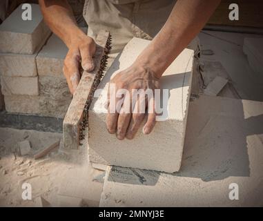 Les mains du sculpteur, qui traite un bloc de pierre blanche sur le bureau avec des outils. Détails de la main Banque D'Images