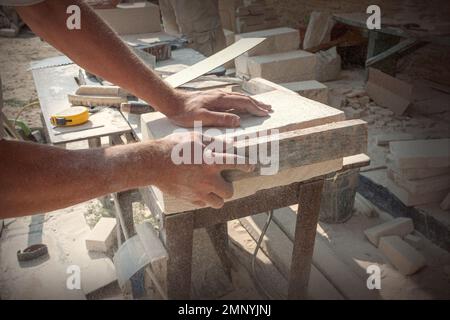 Les mains du sculpteur, qui traite un bloc de pierre blanche sur le bureau avec des outils. Détails de la main Banque D'Images