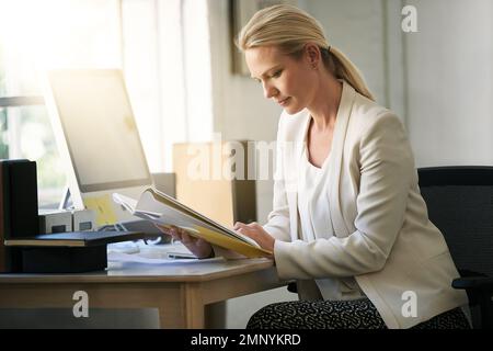 Il est difficile de battre quelqu'un qui ne cède jamais. une femme d'affaires lisant un livre dans son bureau. Banque D'Images