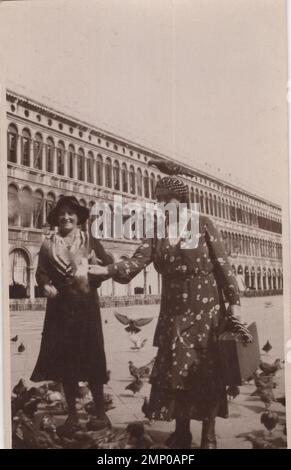 moment vintage / moment drôle vintage / photo vintage / puissance du moment / moments magiques / les dames heureux sont nourrissant des pigeons sur un grand squeat le 1920s. Peut-être est-ce l'Italie ? pas une seule colombe sur la photo. / femmes bien vêtues / pigeon est debout sur la tête de la dame. Banque D'Images