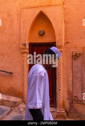 Homme mozabite passant devant une vieille porte à Ksar El Atteuf, Afrique du Nord, Ghardaia, Algérie Banque D'Images