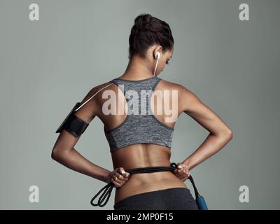 Tout ce dont elle a besoin pour un excellent entraînement. Prise de vue en studio d'une jeune femme tenant une corde sur un fond gris. Banque D'Images