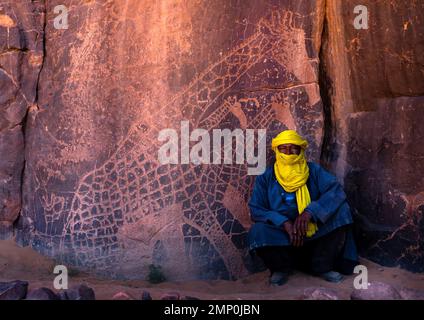 Tuareg près d'une sculpture sur pierre représentant des girafes, Parc national de Tassili n'Ajjer, Tadrar Rouge, Algérie Banque D'Images