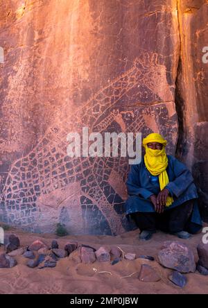 Tuareg près d'une sculpture sur pierre représentant des girafes, Parc national de Tassili n'Ajjer, Tadrar Rouge, Algérie Banque D'Images