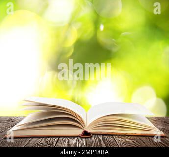 Ouvrez l'ancien livre de couverture rigide sur une table en bois sur fond vert flou Banque D'Images