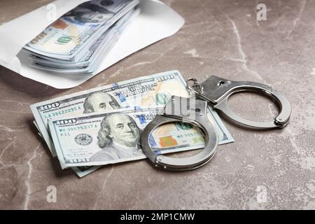 Billets et menottes en dollars sur une table en marbre brun. Concept de corruption Banque D'Images