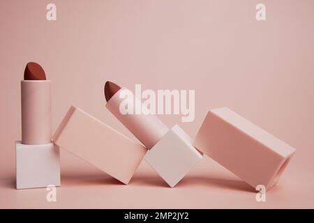 les rouges à lèvres ouverts reposent l'un sur l'autre sur un fond rose Banque D'Images