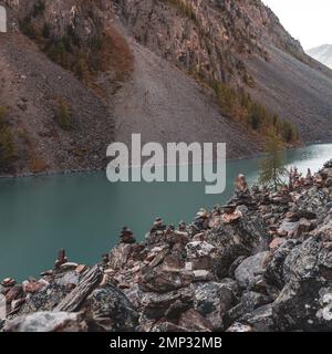 Les pierres posées les unes sur les autres se trouvent sur une côte rocheuse, sur fond de montagne et de lac alpin. Banque D'Images