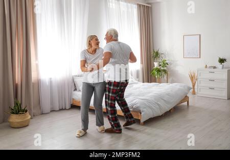 Couple d'âge mûr heureux dansant ensemble dans la chambre Banque D'Images