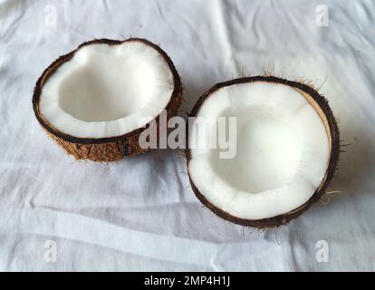 Noix de coco brisée en deux moitiés sur fond blanc. Isolé Banque D'Images