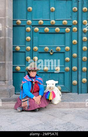 Femme autochtone assise avec un lama devant la porte d'entrée de la basilique la Merced, Cusco, Pérou Banque D'Images