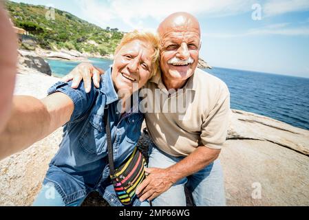 Couple senior en vacances en train de prendre le selfie tout en s'amusant à Giglio Island - excursion en bord de mer - concept de personnes âgées actives Banque D'Images