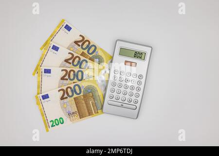 Plusieurs billets de 200 euros à côté d'une calculatrice sur fond blanc comme une photo de studio Banque D'Images