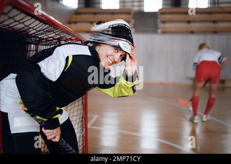 Gros plan de la femme gardien de floorball dans un casque concetating sur le match dans la salle de gym. Banque D'Images