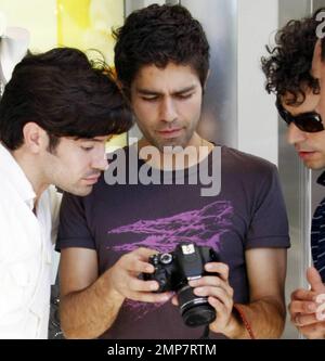 Adrian Grenier, acteur de « l'entourage », marche avec un homme en costume de feu et consulte quelques photos sur un appareil photo numérique pendant que vous filmez dans les rues de Los Angeles. Grenier, qui a récemment été repéré le jour avec la star de télé-réalité Kim Kardashian, aurait signé pour une présentation d'invité sur la série dramatique de l'adolescence '90210'. Los Angeles, Californie. 08/16/10. Banque D'Images