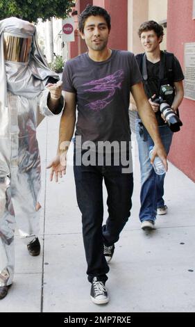 Adrian Grenier, acteur de « l'entourage », marche avec un homme en costume de feu et consulte quelques photos sur un appareil photo numérique pendant que vous filmez dans les rues de Los Angeles. Grenier, qui a récemment été repéré le jour avec la star de télé-réalité Kim Kardashian, aurait signé pour une présentation d'invité sur la série dramatique de l'adolescence '90210'. Los Angeles, Californie. 08/16/10. Banque D'Images