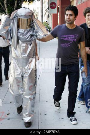 Adrian Grenier, acteur de « l'entourage », marche avec un homme en costume de feu et consulte quelques photos sur un appareil photo numérique pendant que vous filmez dans les rues de Los Angeles. Grenier, qui a récemment été repéré le jour avec la star de télé-réalité Kim Kardashian, aurait signé pour une présentation d'invité sur la série dramatique de l'adolescence '90210'. Los Angeles, Californie. 08/16/10. Banque D'Images