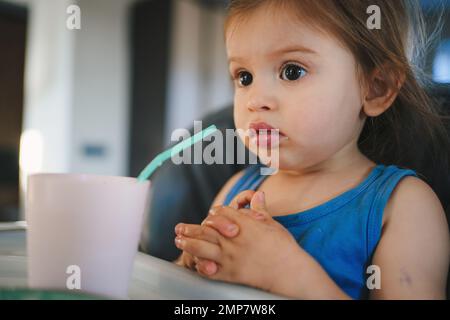 Premier repas de bébé. L'enfant mange seul avec une cuillère. Intérieur de la cuisine. Personne positive. Banque D'Images