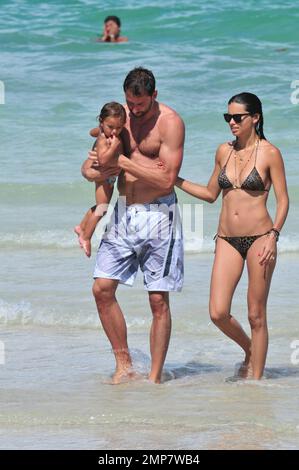Adriana Lima, la fille Valentina et le mari Marko Jaric s'amusent dans le surf sur Miami Beach, FL, 31st juillet 2011. Banque D'Images