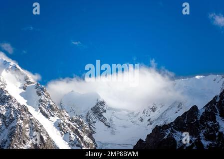 Panorama des sommets des montagnes de pierre rocheuse avec des langues de glaciers et de neige couvertes de nuages blancs et de brouillard en Altaï pendant la journée. Banque D'Images