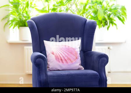Concept de produits personnalisables : chaise à dossier en bleu rétro avec coussin de projection personnalisé et imprimé de coquillages roses. Banque D'Images