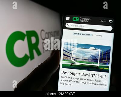 Personne tenant un smartphone avec le site Web de l'organisation américaine Consumer Reports (CR) à l'écran devant le logo. Concentrez-vous sur le centre de l'écran du téléphone. Banque D'Images