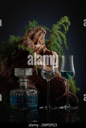 Gin bleu sur fond noir. Les agences Juniper et le vieux bois flotté sont en arrière-plan. Banque D'Images