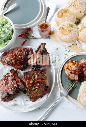 Côtes de porc avec sauce barbecue et oignons avec salade et pain sur fond de table de cuisine Banque D'Images