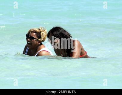 Alexandra Burke porte un bikini couleur pêche à la plage comme elle aime un autre jour au soleil. Tout en faisant une promenade sur la plage dans une robe longue rayée tendance Burke s'est arrêté pour ramasser des coquillages avant de prendre un plongeon dans l'eau de refroidissement. Plus tard, la chanteuse a montré ses multiples bracelets perlés comme elle a texté sur son unique téléphone cellulaire clouté. Miami Beach, Floride. 3/7/11 Banque D'Images